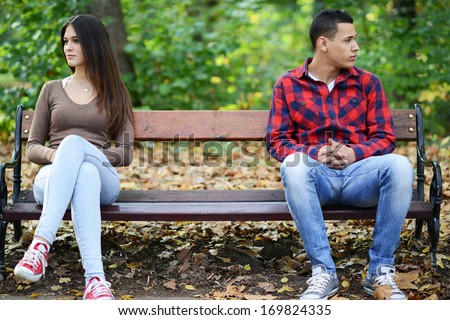 Young Couple In Quarrel Sitting On Bench In Park