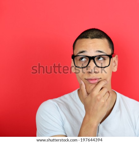 Portrait of a funny businessman with fingers on chin while thinking against red background