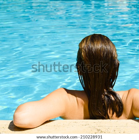 Back view of relaxed woman in swimming pool with blue water