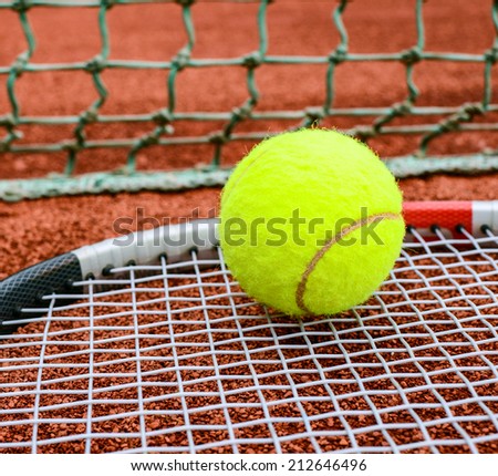 Tennis racket with ball on it clay on clay court