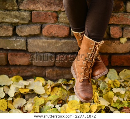 Conceptual image of legs in boots on the autumn leaves - Walking in nature