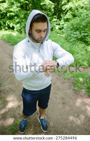 Runner on mountain trail looking at sports smart watch