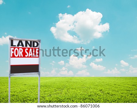 Land for sale sign on empty green field