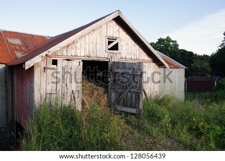The door of an old gray barn is left open for ventilation, so the hay inside would dry better