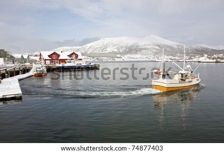 Fishing boat going to sea at Stokmarknes harbour at winter