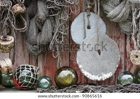 Fishing nets, round stone sinkers, cork and glass floats at boathouse wall in Norway