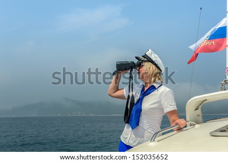 The woman-captain of the small size vessel looks in the field-glass...