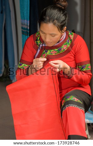 Young woman - dressmaker embroider at the entrance to his atelier