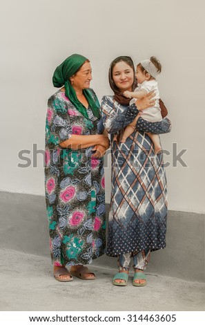 Tajik family in the background of the walls of the house - the grandmother, mother, daughter