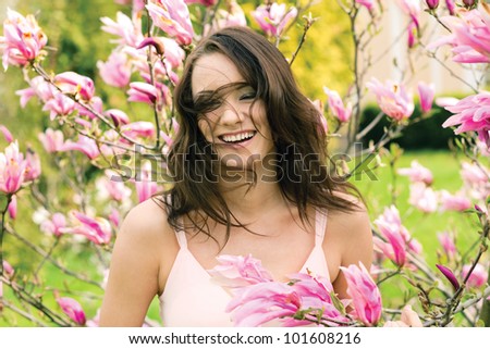 Outdoor portrait of happy young natural beauty woman with flying hair in spring flowers
