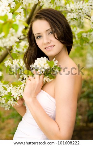 Outdoor spring portrait of natural beauty woman looking at camera with cherry blossom