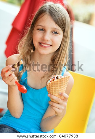Happy little girl with ice cone in ice cream parlor