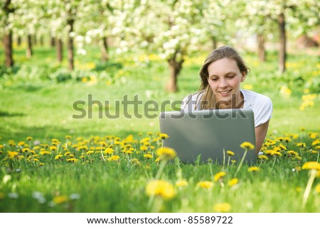 Young woman with notebook in park looking at notebook computer