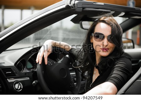 Sexy young woman with black sport cabriolet in summer
