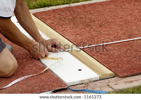 An official measures  the distance in the long jump event during a college track meet.