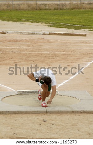 A competitor in the men\'s shot put event during a college track meet.