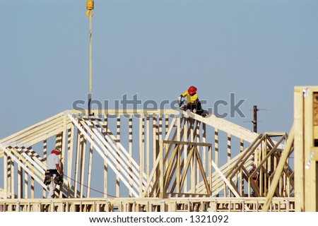 Workers move a roof truss into position on a new house under construction in a suburban neighborhood.