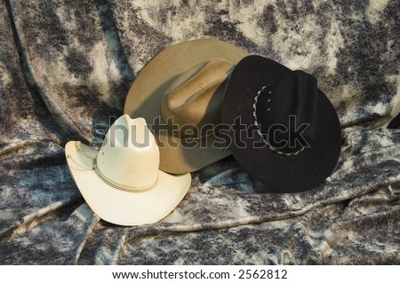 Three cowboy hats. black hat, brown hat and straw hat.