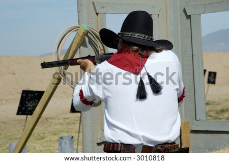 Competitor shooting a lever action rifle in a cowboy shoot competition.