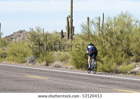 a cyclist bikes on a desert road