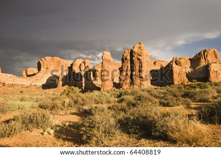 The sun breaks out over Arches National Park after a rainstorm passes over. Dark clouds in the background.
