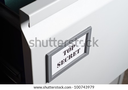 Close up of a partly opened filing cabinet drawer with a label marked \'Top Secret\' at the front.  Landscape orientation.