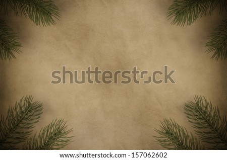 Christmas tree branches set in the corners of a dark parchment background to create a frame.