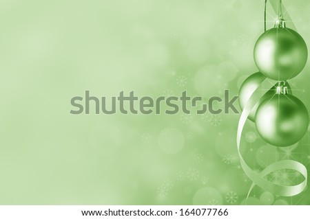 Festive green Christmas baubles and spiral streamer on the right. Circles of bokeh glow, sparkling stars and snowflakes in the background fading towards solid colour copy space on the left side.