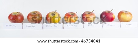 A horizontal row of seven organic red apples, labeled with the days of the week, to illustrate the motto 'An apple a day keeps the doctor away'.  White background.