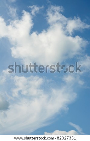 Natural shot of a blue sky with white fluffy clouds.  Portrait (vertical) orientation.