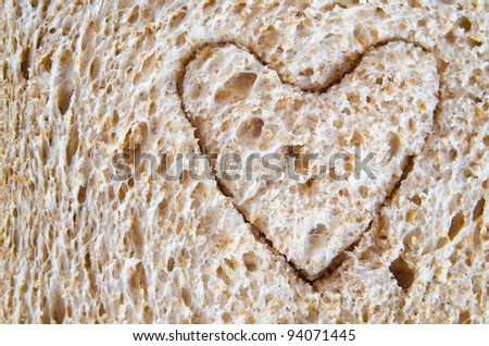 Close up (macro) of wholemeal bread with a heart shape cut into it, to illustrate love or a healthy heart diet.