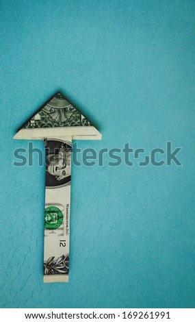 origami dollar arrow pointing up, on blue