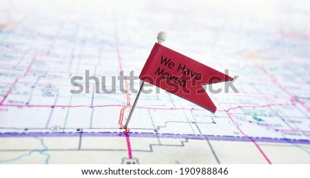 Closeup of red pin flag on a map with We Have Moved text
