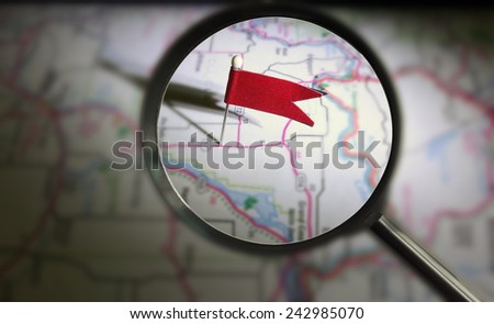 Pin flag locator lit on a map with magnifying glass