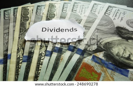 Closeup of hundred dollar bills with Dividends news headline