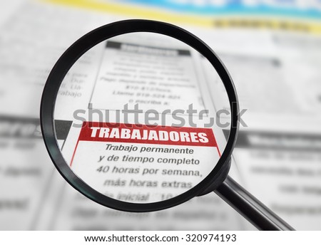 Employment section of a Spanish language newspaper with magnifying glass.  Trabajadores (Workers) text is sharp