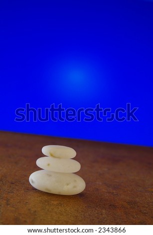 Smooth white stones balancing against tilted blue background