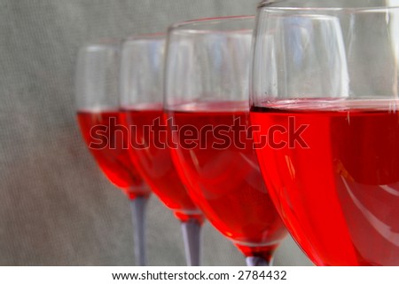 Four glasses of red wine on neutral textured background