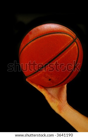 Basketball player reaching with ball in hand, on black