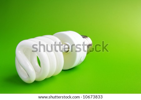 Compact flourescent light bulb on green (green energy)