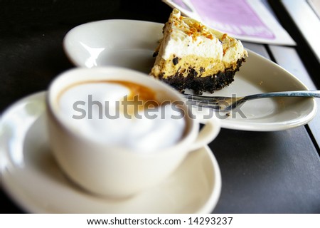 Cup of  frothy coffee and cake, cake is sharp