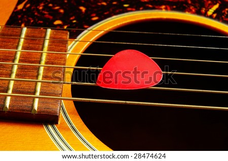 closeup of a guitar pick on acoustic guitar strings