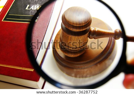 magnifying glass examining a judges court gavel, with law book