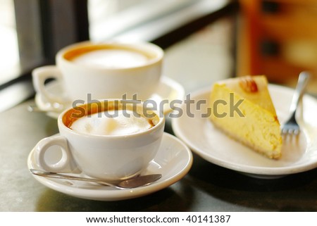 pair of cappuccino coffees and slice of pumpkin pie or pumpkin cheesecake