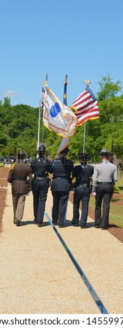 Police Officers march in formation carrying flags during the police memorial ceremony.