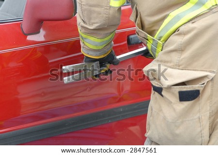 Fireman cutting into a wrecked car to remove the driver .