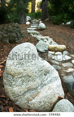 Path of rocks with large rock in forground in a forest