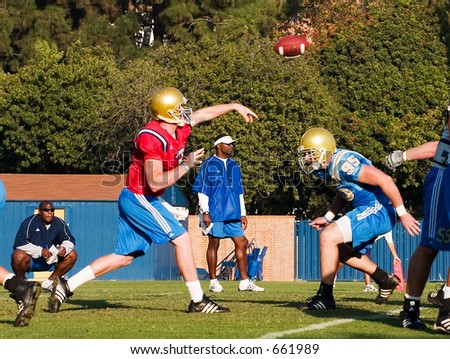 UCLA Bruins Football team practicing.  Quarterback throwing the ball right before getting sacked