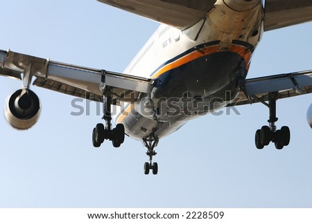 Close image of a jet plane landing with landing gears down
