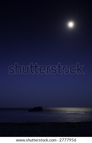 Leo Carillo Beach just outside of Malibu.  The moon shines over a rock in the ocean, reflecting in the water